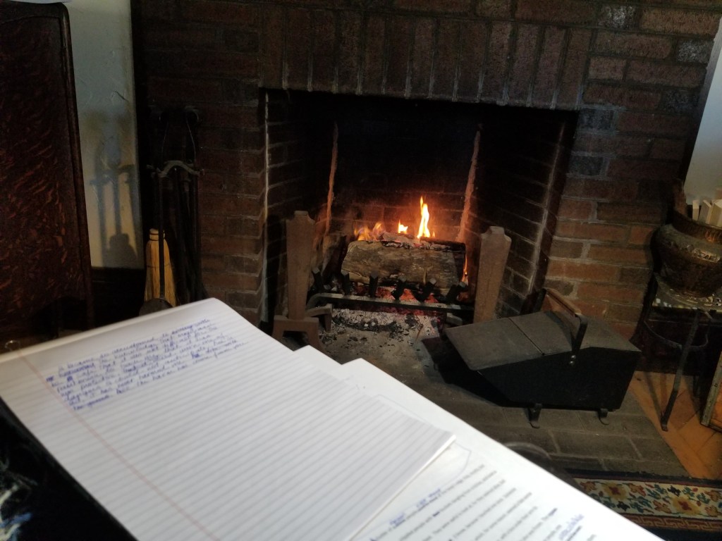 My printed and handwritten pages, with the fire glowing in the background.
